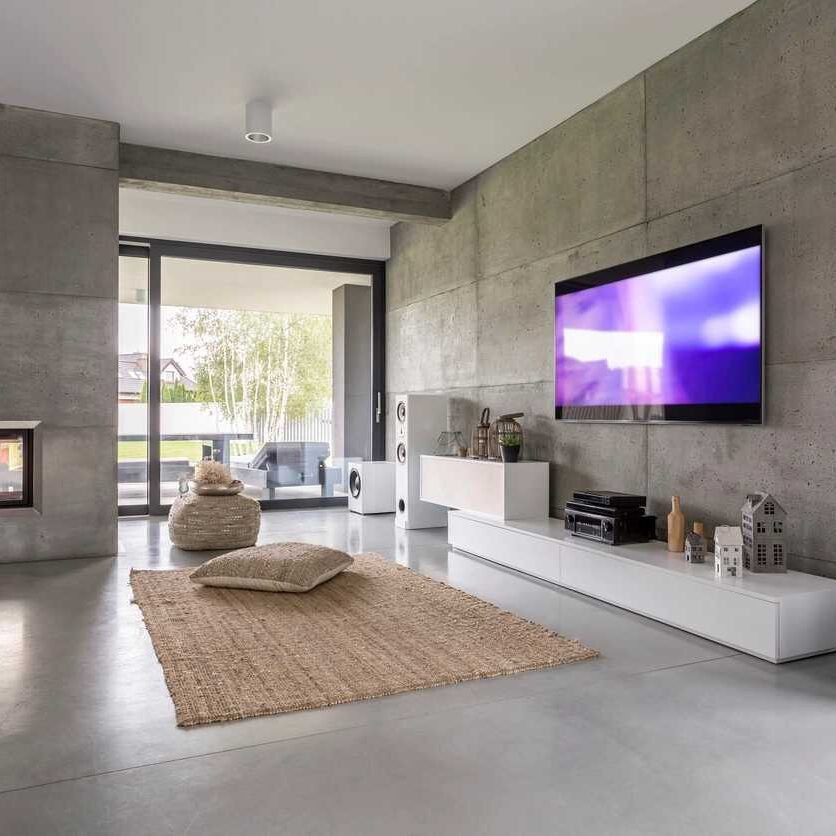 Wall-mounted TV with surround sound speakers in a stylish living room.